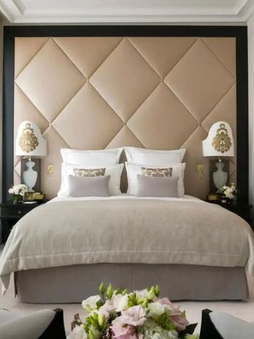 Modernes Hotelzimmer mit großem Bett, dekorativer Rückwand und frischen Blumen