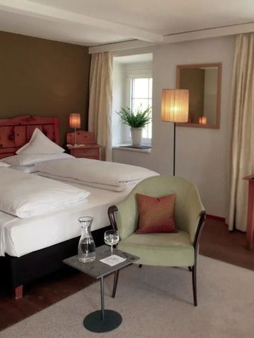 Elegantes Doppelzimmer mit gemütlicher Sitzecke und natürlichem Licht