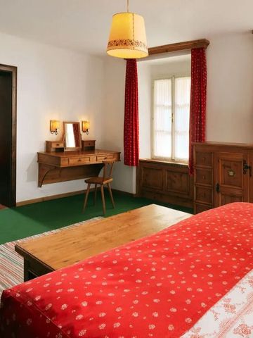 Elegantes Gästezimmer mit rotem Bettzeug und Holzschreibtisch