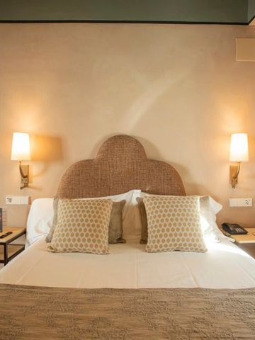 Doppelbett mit eleganten Kissen und warmem Beleuchtung.