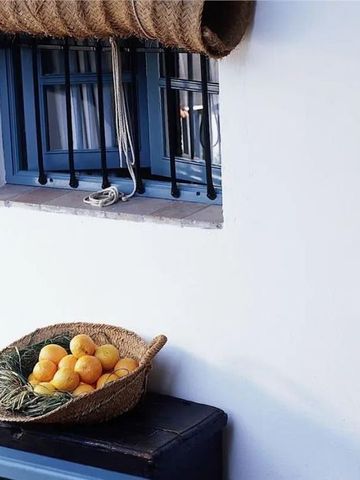 Korbschale mit Orangen auf Terrassendekoration, blau-weiße Fensterläden
