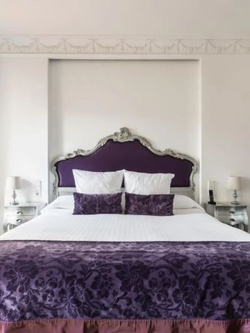 Elegantes Doppelbett mit dekorativem Kopfteil und feinen Stoffen