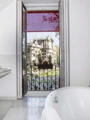Badezimmer mit freistehender Badewanne und Blick auf historische Architektur