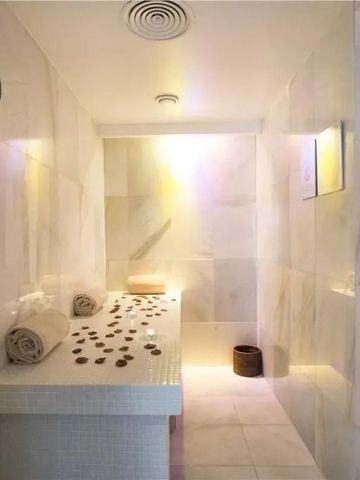 Wellnessraum mit Marmorwänden und Massagetisch bedeckt mit Rosenblättern