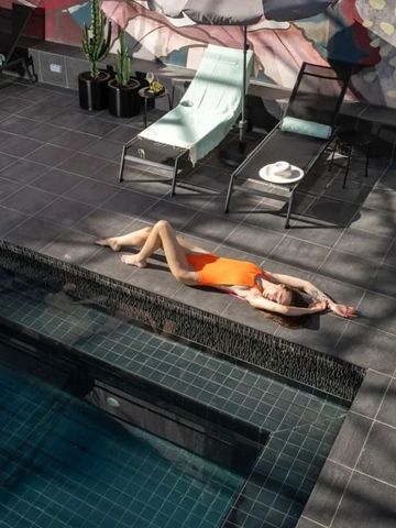 Frau in einem orangefarbenen Badeanzug am Rand eines modernen Pools