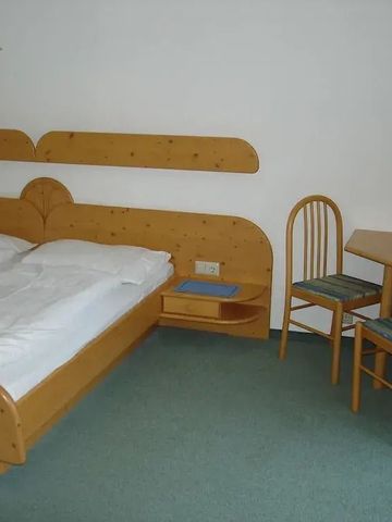 Einfach eingerichtetes Doppelzimmer mit Holzmöbeln und kleinem Tisch