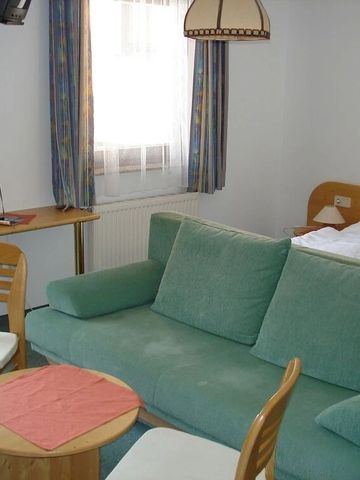 Gemütliches Einzelzimmer mit grünem Sofa und heller Einrichtung