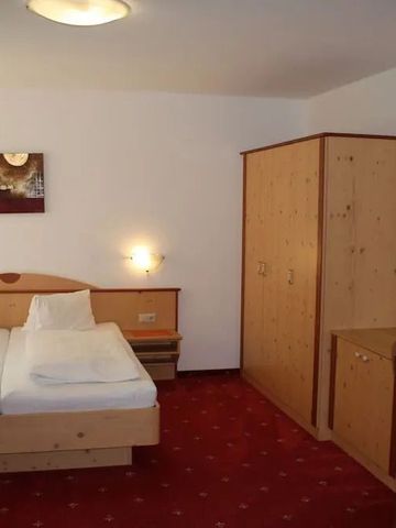 Gemütliches Hotelzimmer mit Doppelbett, roter Teppich und Holzschränken