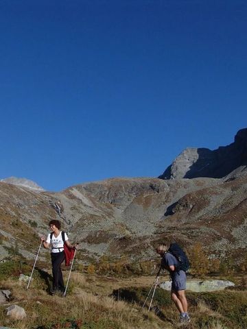 Menschen wandern in alpiner Berglandschaft unter klarem Himmel