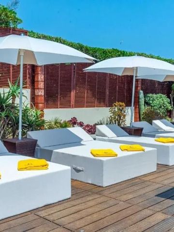 Sonnige Terrasse mit bequemen Sonnenliegen und weißen Sonnenschirmen