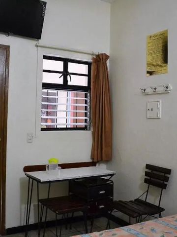 Einfach eingerichtetes Zimmer mit Tisch, Stühlen und Bett.