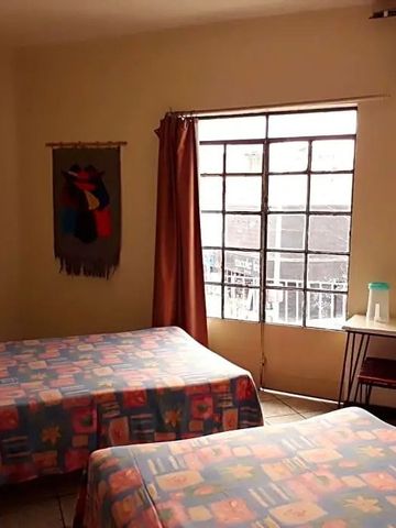 Zimmer mit zwei Betten und großem Fenster mit Blick nach draußen.