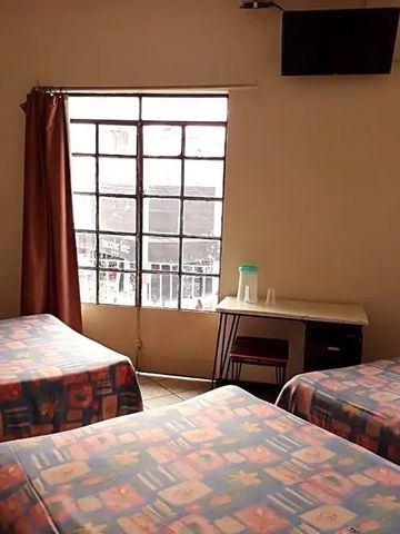 Helles Zimmer mit drei Einzelbetten und einem großen Fenster