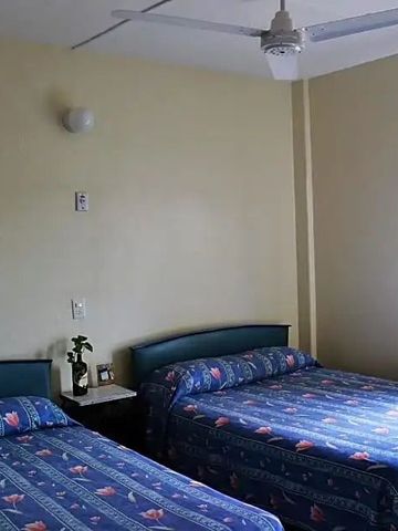 Zimmer mit zwei Doppelbetten, Ventilator und Fenster