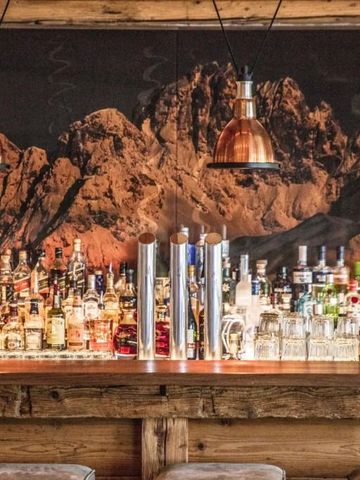 Stilvolle Bar mit einer großen Auswahl an Spirituosen vor Bergkulisse