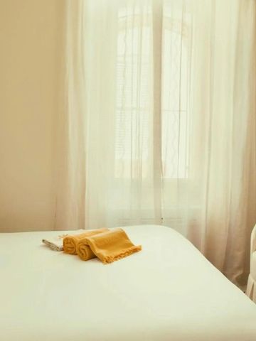 Hell beleuchtetes Zimmer mit einem Doppelbett und Vorhängen