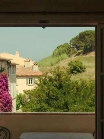 Blick von einem Fenster auf mediterrane Landschaft und Häuser mit Bougainvillea.