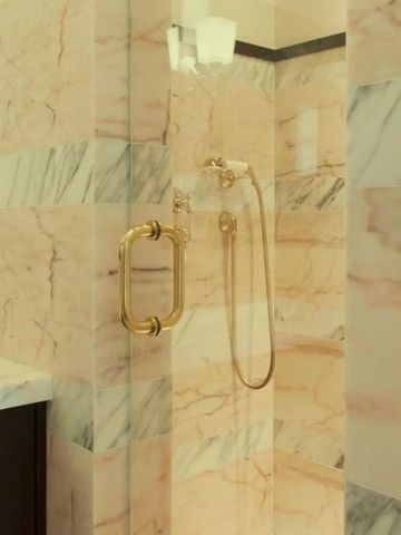 Dusche mit goldenen Armaturen in einem edlen Badezimmer aus Marmor.