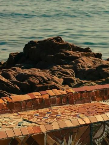 Mosaik-Terrasse mit Blick auf das Meer und Felsen im Hintergrund