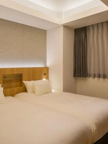 Modernes Hotelzimmer mit zwei Einzelbetten und sanft beleuchteter Decke