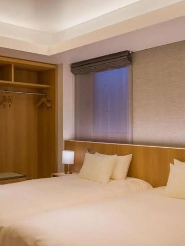 Geräumiges Hotelzimmer mit offener Holzgarderobe und zwei Einzelbetten