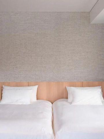 Zwei Einzelbetten mit weißer Bettwäsche in einem modern eingerichteten Hotelzimmer