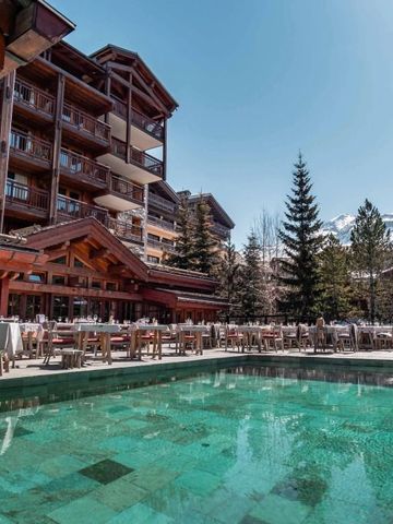 Hotelansicht mit Pool im Vordergrund und alpiner Architektur im Hintergrund