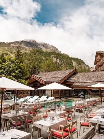 Außenbereich des Hotel Le Blizzard mit Terrasse und Bergen im Hintergrund.