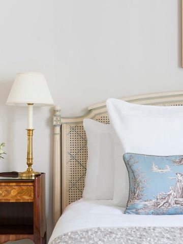 Elegantes Schlafzimmer mit weißer Bettwäsche und blauem Zierkissen