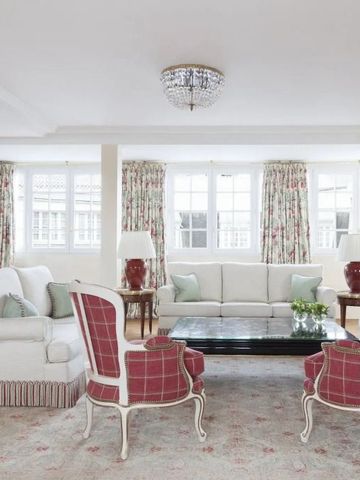 Helle Lounge mit weißen Sofas und roten Sesseln