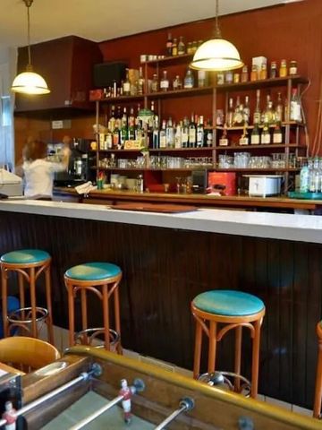 Gemütliche Hotelbar mit Holzhockern und gut bestücktem Regal im Hintergrund