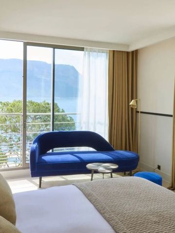 Helles Schlafzimmer mit Terrasse und Meerblick durch große Fenster.