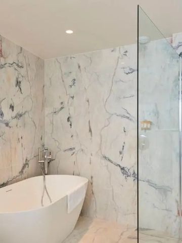 Elegantes Badezimmer mit freistehender Badewanne und Marmorwänden.