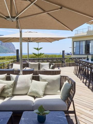 Geräumige Dachterrasse mit bequemen Sofas und Sonnenliegen am Meer