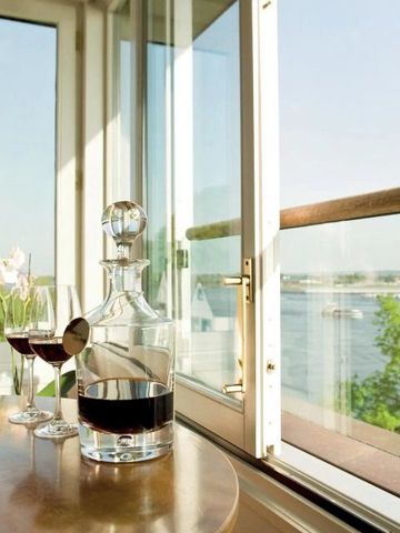 Wein und Dekanter auf einem Tisch mit Blick auf einen Fluss durch ein offenes Fenster