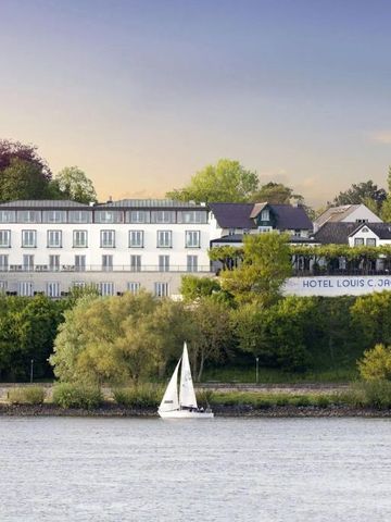 Hotelansicht von der Elbe aus mit Boot und grüner Umgebung
