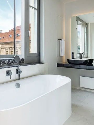 Elegantes Badezimmer mit freistehender Badewanne und Blick auf die Stadt