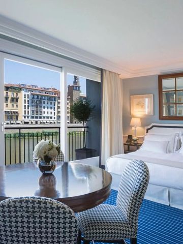 Luxuriöses Hotelzimmer mit Esstisch, hellen Farben und Blick auf den Fluss Arno