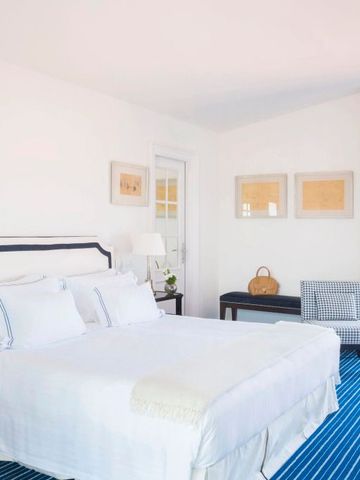 Lichtdurchflutetes Schlafzimmer mit blauem Teppich und stilvollem Dekor