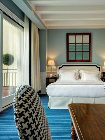 Elegantes Zimmer mit Balkon und Blick auf den Fluss. Hell dekoriert mit Blau- und Weißtönen.