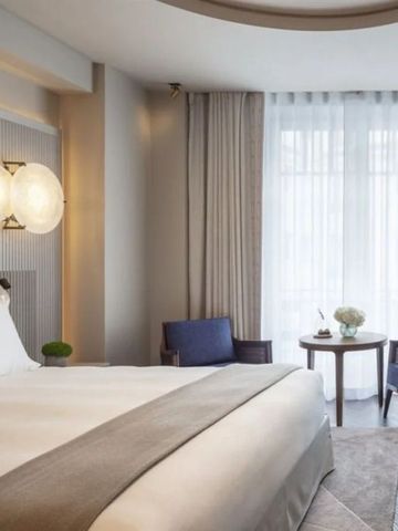 Lichtdurchflutetes Zimmer mit großer Fensterfront und eleganter Einrichtung