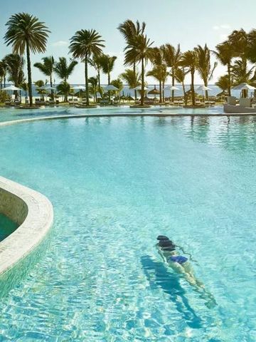 Blick auf den Infinity Pool mit Palmen im LUX* Belle Mare Hotel