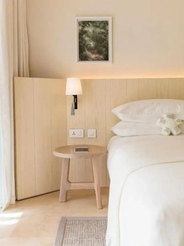 Detailaufnahme eines gemütlichen Bettes mit Holzelementen und Nachtlampe