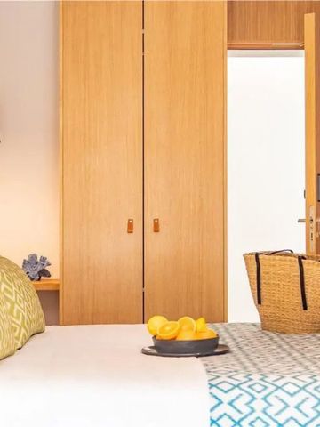 Hotelzimmer mit hellem Holzschrank und dekorativen Kissen auf dem Bett.