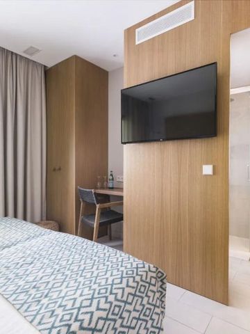 Modernes Hotelzimmer mit Holzakzenten und großem Flachbildfernseher.