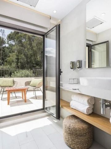 Helles Badezimmer mit Blick auf grüne Terrasse durch offene Glastür