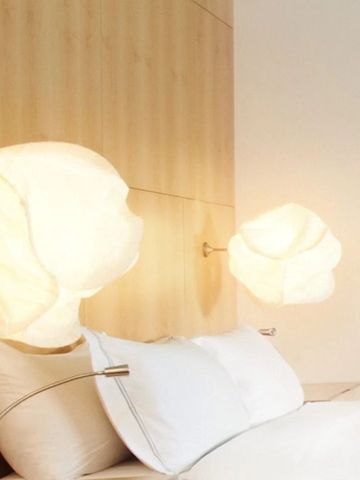 Moderne Zimmerlampe über einem eleganten Doppelbett mit weißer Bettwäsche