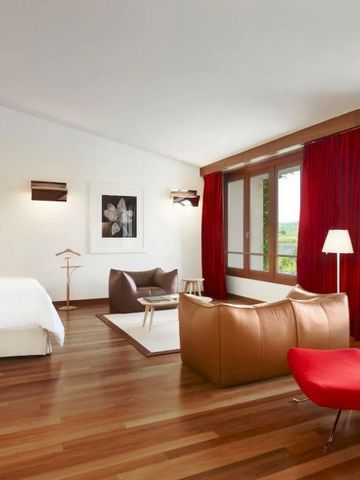 Modern eingerichtete Suite mit rotem Vorhang und Ledersesseln