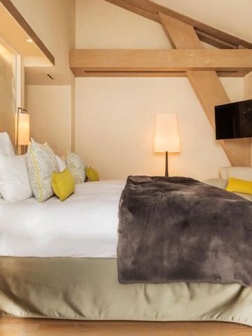 Zimmer mit schrägen Holzbalken und flauschiger Bettdecke