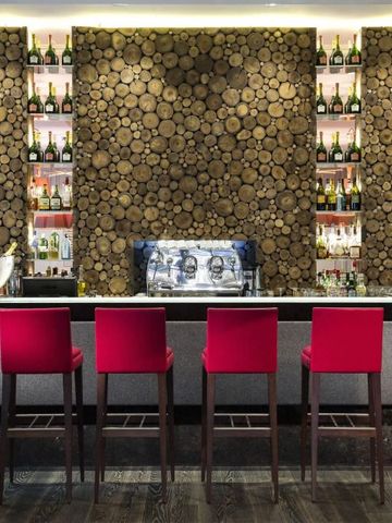 Stilvolle Bar mit roten Barhockern und Regalen voller Flaschen